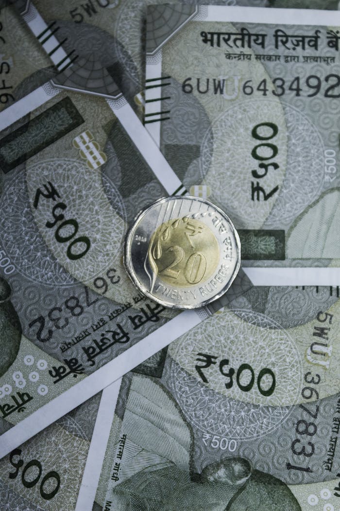Close-up of Indian 500 rupee banknotes with a rupee coin on top, showcasing currency and wealth.